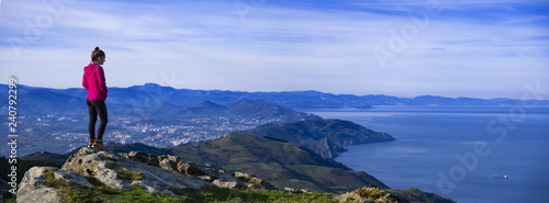 Girl on top of the mountain looking at the sea with the city of San Sebastian in the background.