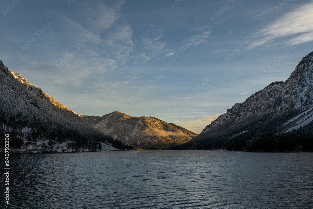 morning at lake plansee in winter with sunrise and snowy mountains
