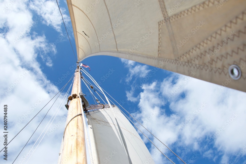 Fototapeta premium Looking up the mast on a sailing yacht, focussed on the flag at the masthead