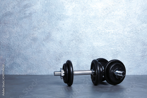 Pair of adjustable dumbbells on floor near color wall. Space for text