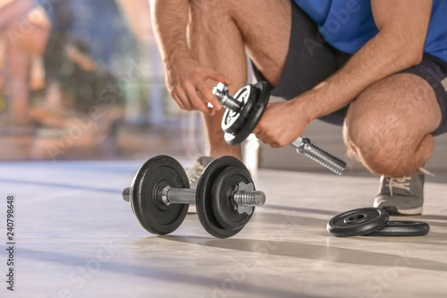 Male athlete with adjustable dumbbells indoors. Space for text photo
