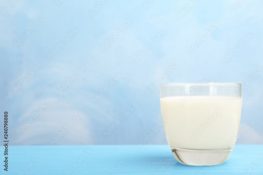 Glass with fresh milk on table against color background. Space for text