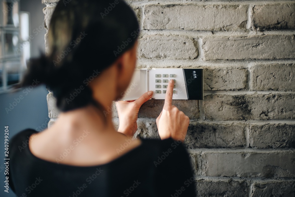 Young woman entering security pin on home alarm keypad. - obrazy, fototapety, plakaty 
