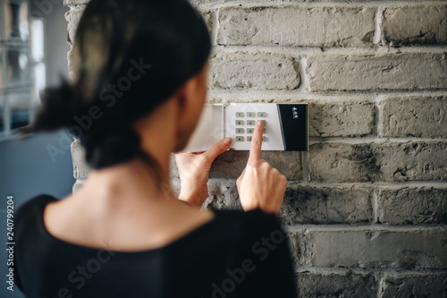 Young woman entering security pin on home alarm keypad. photo