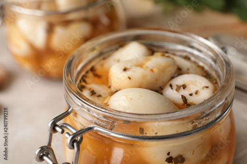 Preserved garlic in glass jar on table, closeup