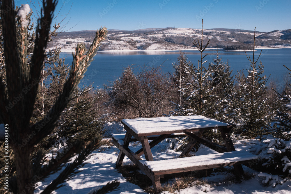 Beautiful winter photo  in the park with woden bench and blue Vlasina lake in the background