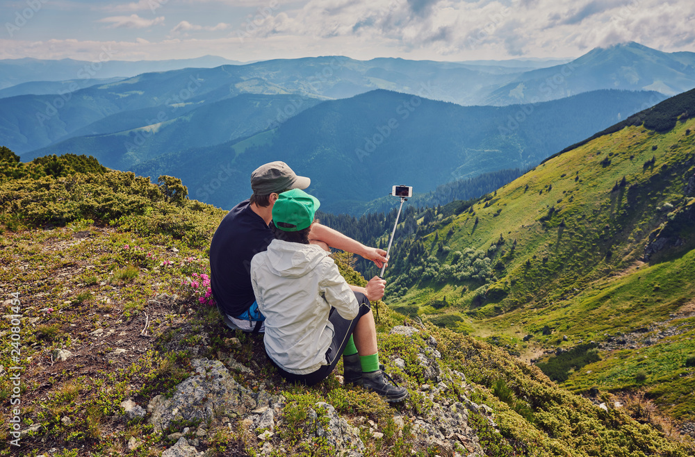 Fototapeta premium Young couple hiking taking selfie with smart phone.