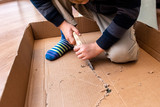 Child playing with a cardboard box and a saw to build.