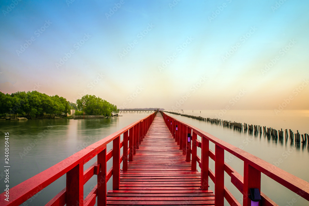 Fototapeta premium Długi czerwony most światło słoneczne niebo drzewo na plaży morze, czerwony most Samut Sakhon Tajlandia