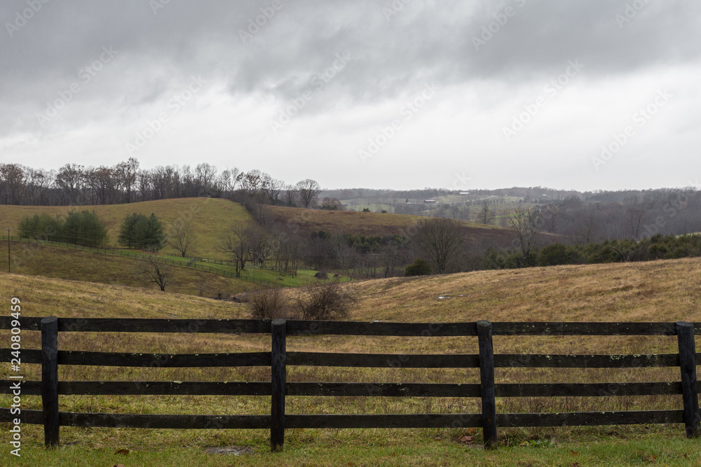 Brown ranch fence in front grass covered rolling hills