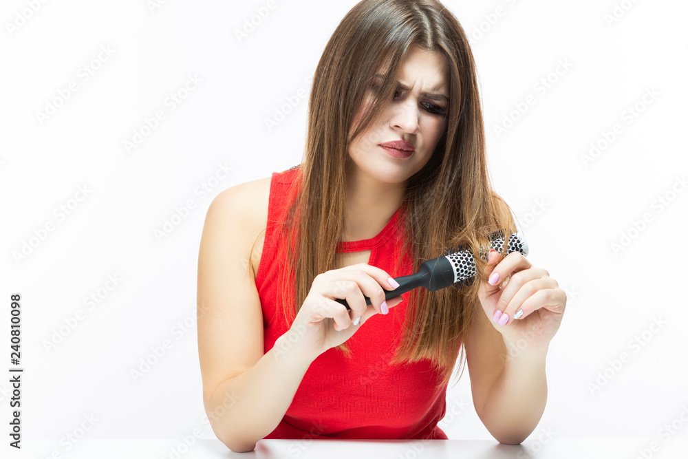 Hairloss and Baldness Issues. Young Caucasian Female Having Hair Problems. Checking Hair in Hairbrush. Posing in Red Dress Against White. Hairloss and Baldness Issues. Young Caucasian Female Having Hair Problems. Checking Hair in Hairbrush. Posing in Red Dress Against White.