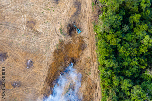 Birds eye view of tropical rainforest deforestation.  An earth mover removes trees which are then burnt photo