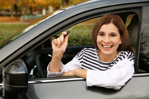 Happy woman holding car key in auto. Driving license test