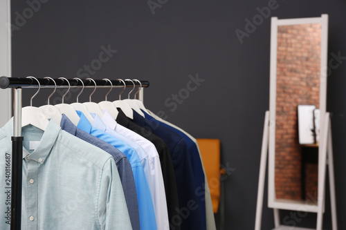 Wardrobe rack with stylish clothes in dressing room. Space for text