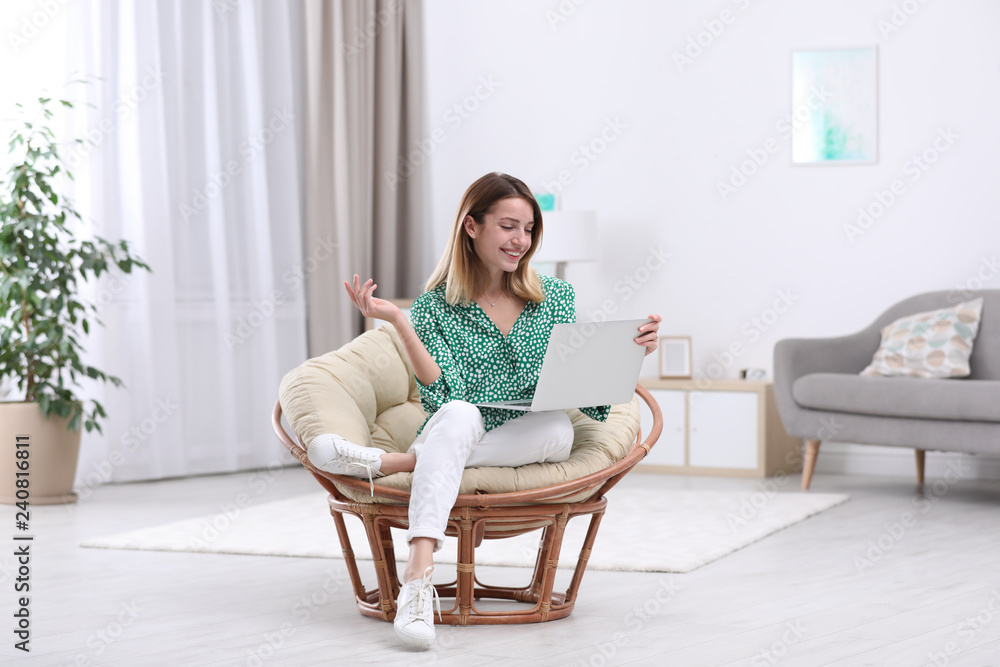 Attractive young woman with laptop in armchair at home Attractive young woman with laptop in armchair at home