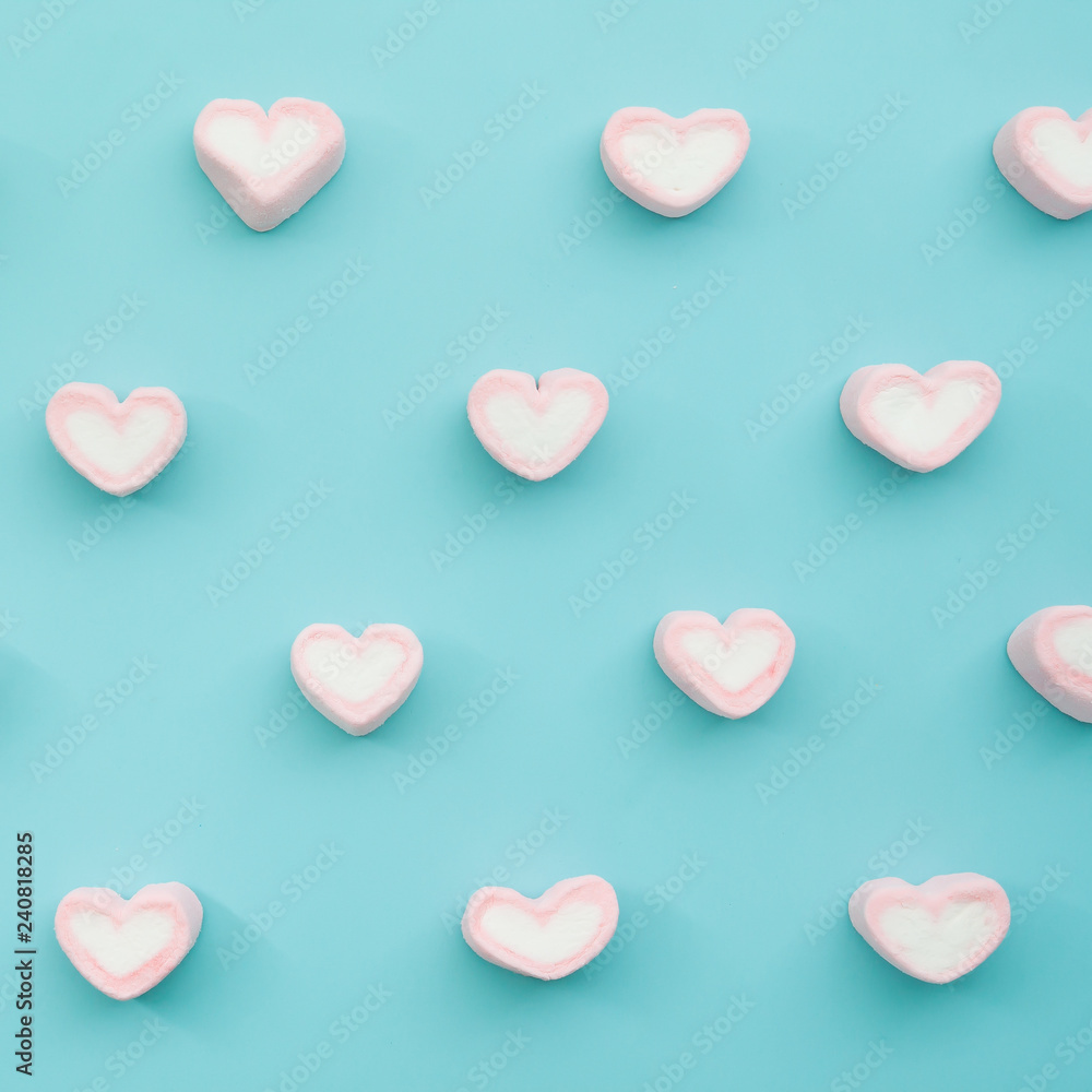 Flat lay top view tasty appetising concept, minimal pink heart shape marshmallow pattern on blue pastel background and copy space
