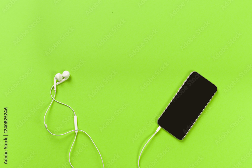 Mobile phone with white earphones on colour backgroung, top view Mobile phone with white earphones on colour backgroung, top view