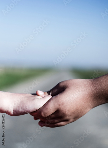 Refugee girl and white girl holding hands while walking on the road © bettysphotos