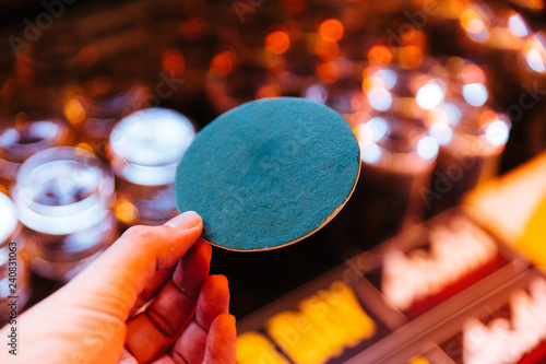 Green circle coaster paper holding with left hand with blur background.