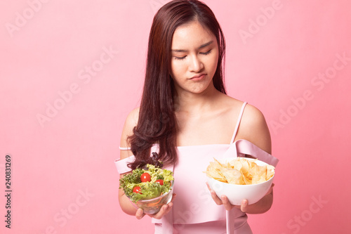Young Asian woman with potato chips and salad.