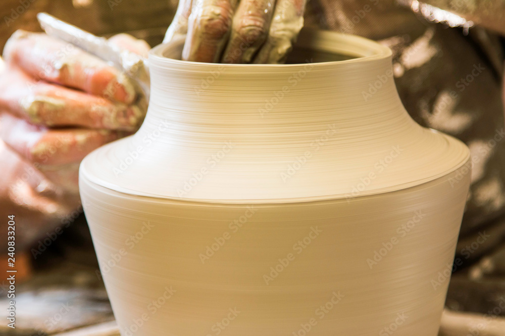      Artist potter in the workshop creating a ceramic vase. Hands closeup. Twisted potter's wheel. Small artistic craftsmen business concept. 