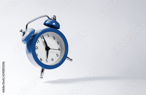 The dark blue alarm clock bounces against the background.