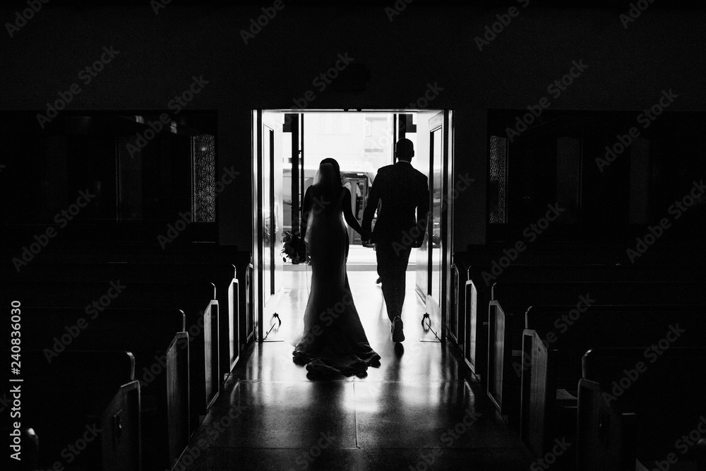 bride and groom walking down church aisle after ceremony in black and white