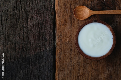 Plain organic yogurt in wooden bowl and wood spoon on wood texture background