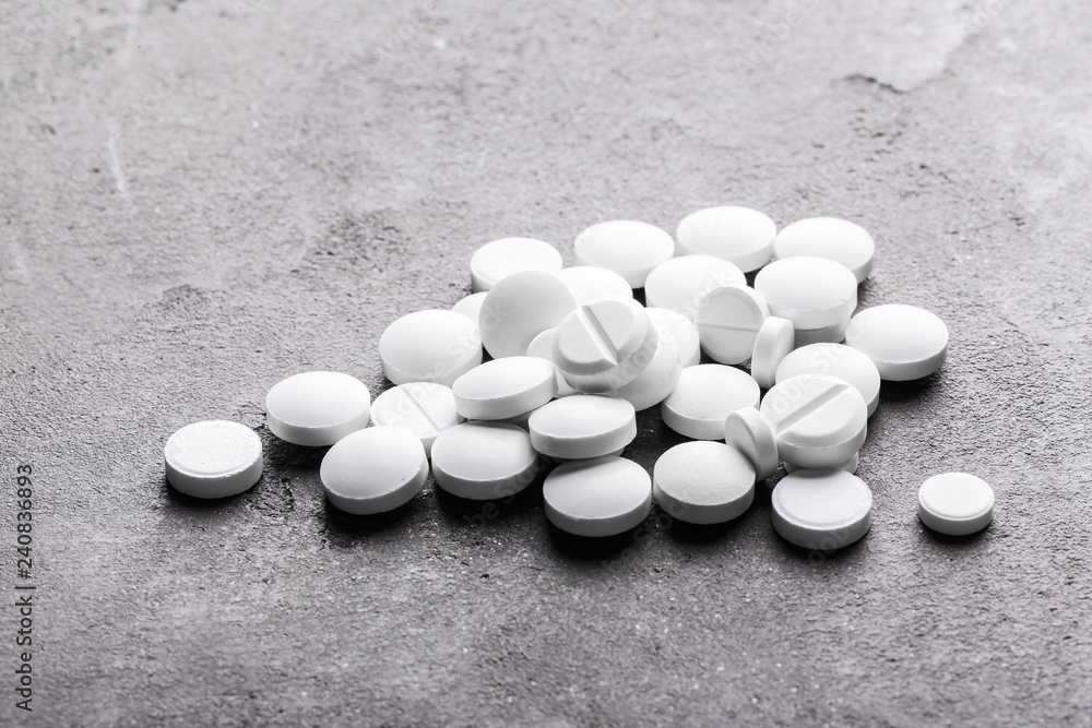 White pills on grey textured background White pills on grey textured background