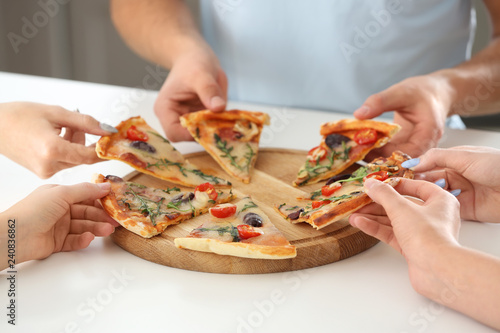 Young people sharing tasty pizza at table, closeup
