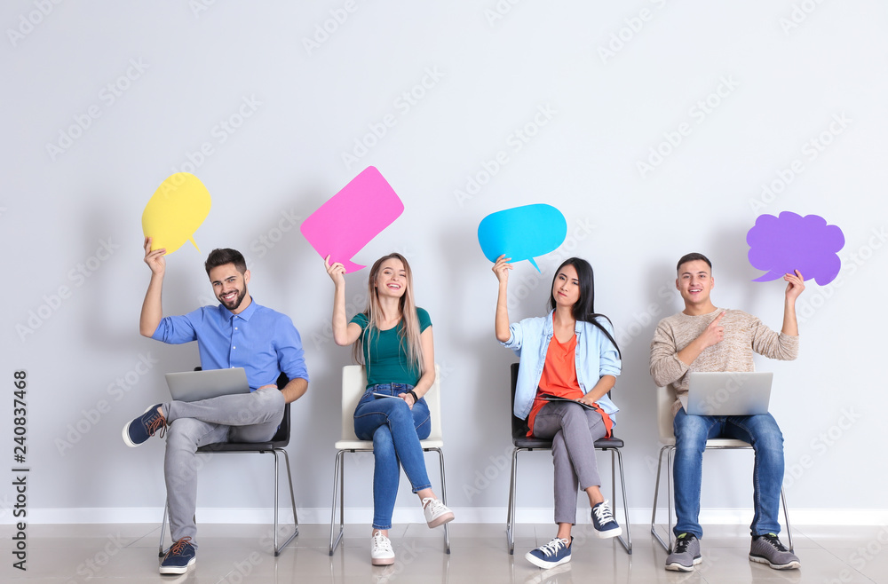 Naklejka premium Young people with blank speech bubbles sitting near white wall
