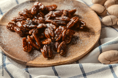 Plate with candied pecan nuts on table