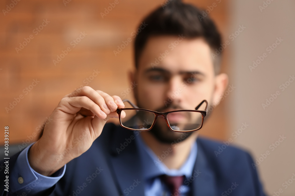 Young man with bad sight holding eyeglasses Young man with bad sight holding eyeglasses