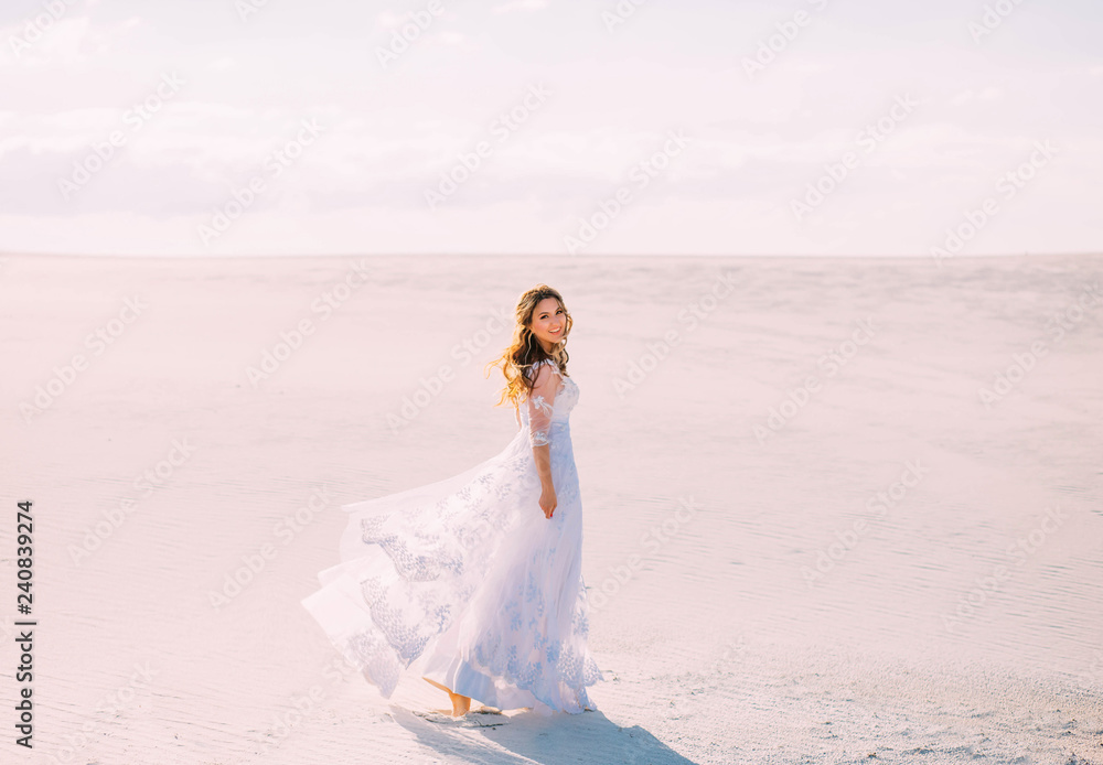 A lovely sweet girl in an elegant white dress with transparent sleeves walks on the white sand of the Maldives during her summer vacation and smiles brightly and sweetly. positive sincere emotions A lovely sweet girl in an elegant white dress with transparent sleeves walks on the white sand of the Maldives during her summer vacation and smiles brightly and sweetly. positive sincere emotions