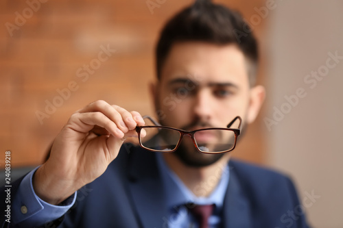 Young man with bad sight holding eyeglasses