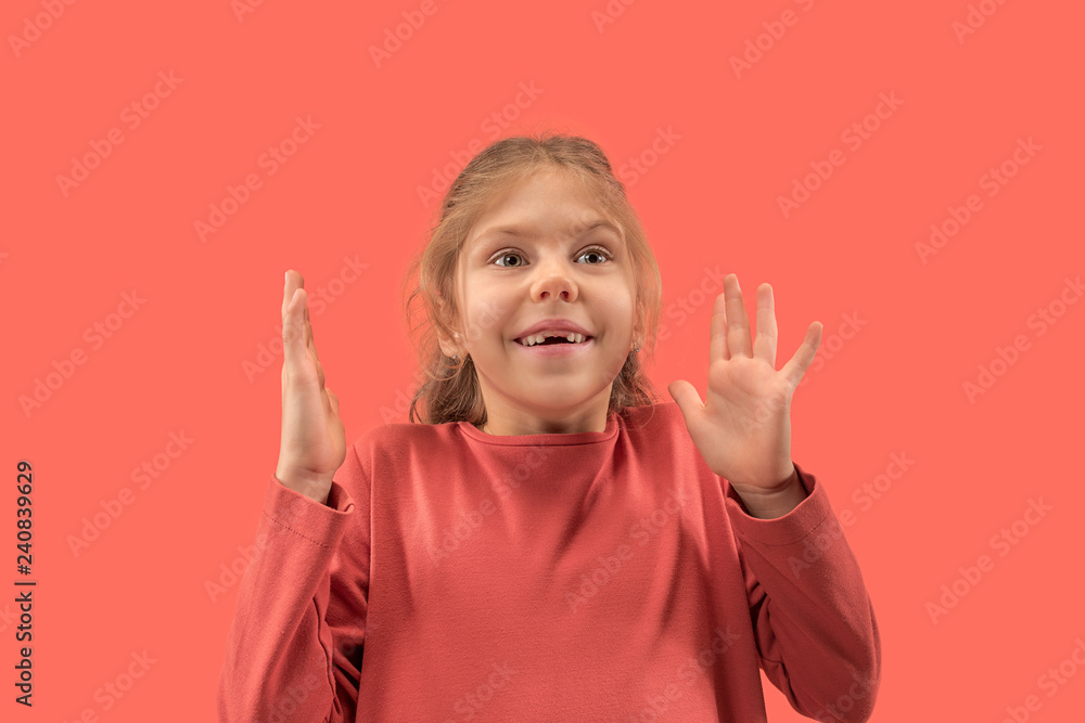 Cute happy little surprised girl in coral dress with long hair looking to camera at studio. Human emotions and facial expression over trendy color Cute happy little surprised girl in coral dress with long hair looking to camera at studio. Human emotions and facial expression over trendy color