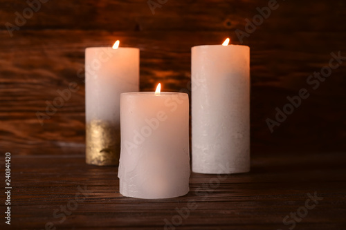 Burning candles on wooden table in darkness