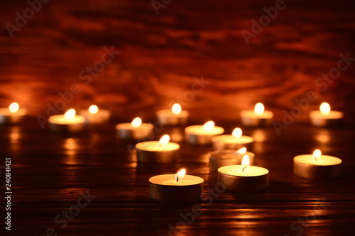 Many burning candles on table in darkness