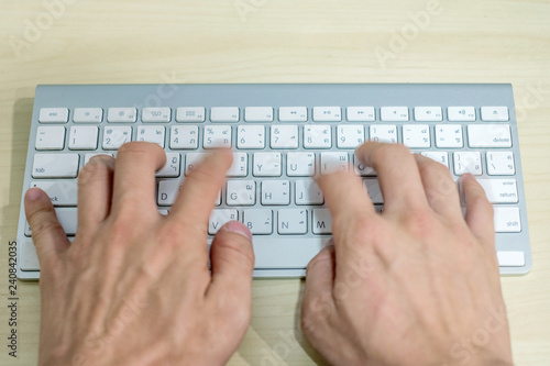 Hand professional programmer typewriting on modern keyboard on wooden desk