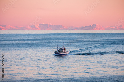 Fishing boat cruising on arctic sea to fish at sunset in winter © Mumemories