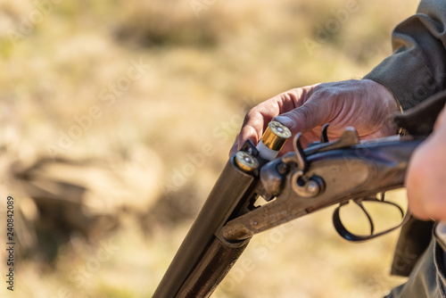 Fotografie Hunter equips the retro double-barreled shotgun with cartridges, close up