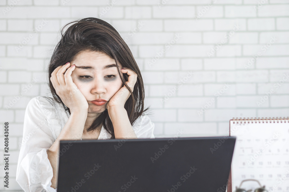 sleepless Asian woman feeling tired and sleepy at workplace eyes