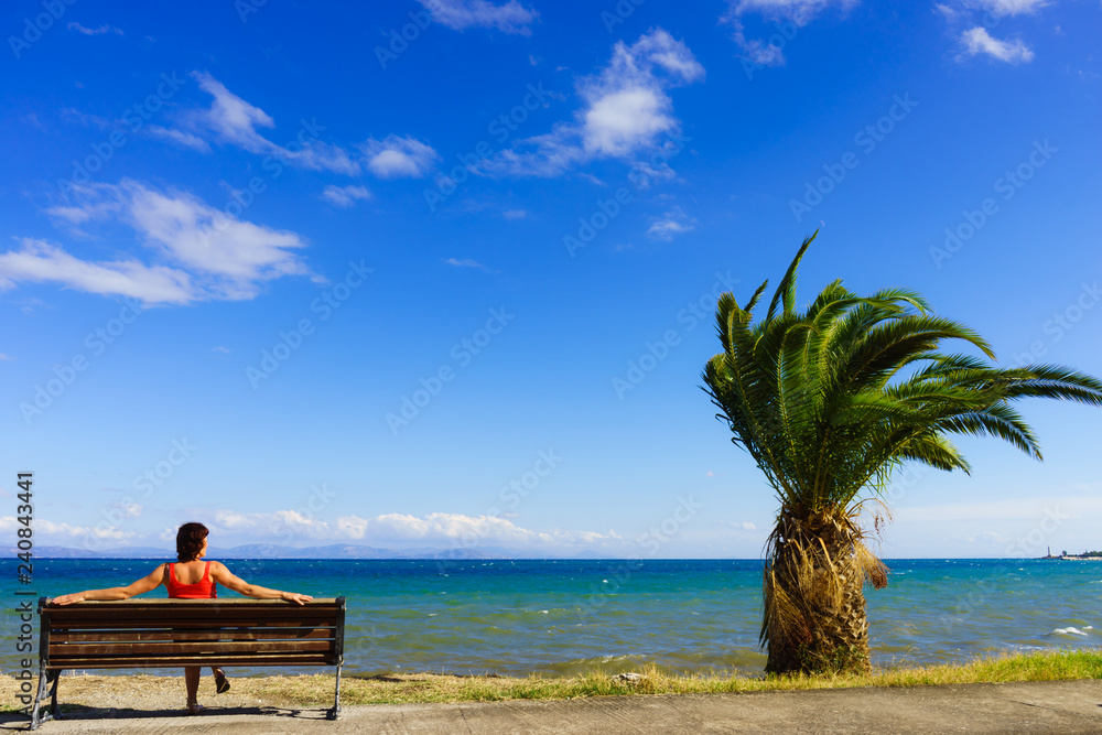 Tourist woman on bench enjoying sea view
