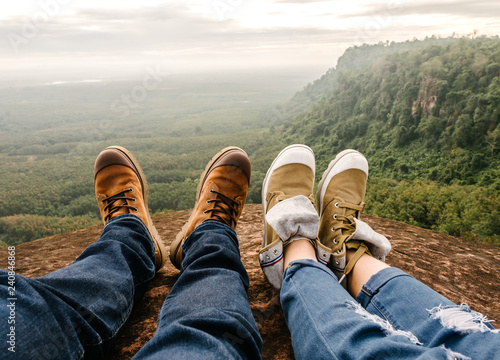 trekking shoes on feet of couple of travelers hikers sitting on top of the mountain in bung karn with the beautiful view, Bung karn in Thailand photo