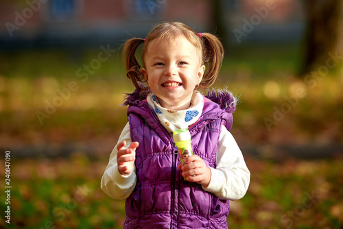 Little girl child enjoying playing with soap bubbles in autumn park
