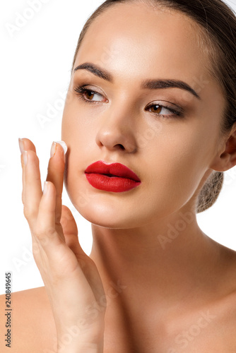 beautiful girl with red lips applying cream on face isolated on white