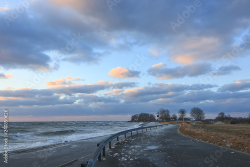 deserted road with waves at the shoreline in scenic stormy winter coastal landscape at the Baltic Sea