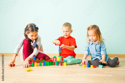 Three friends building with blocks on a floor