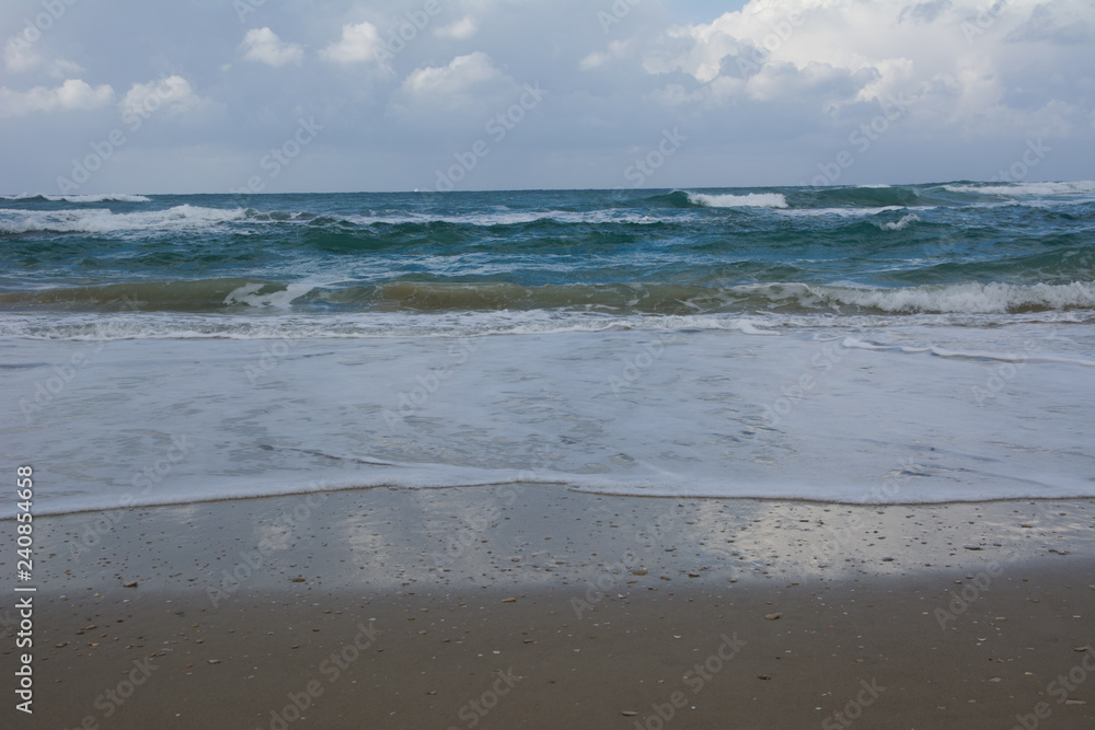 Waves crashing on shoreline with moody dramatic sky