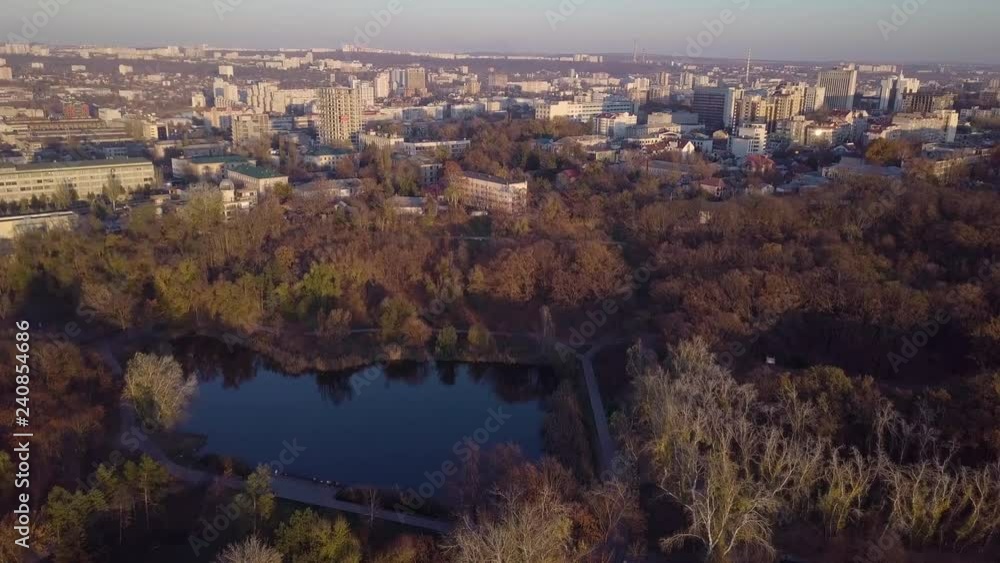 Picturesque aerial 4k drone flight over calm small city cityscape with mirror surface lake in park at sunset. Kishinev, Moldova. Picturesque aerial 4k drone flight over calm small city cityscape with mirror surface lake in park at sunset. Kishinev, Moldova.